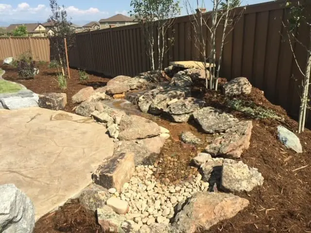 Water-wise Colorado landscape with artificial turf, rock beds, and outdoor living design