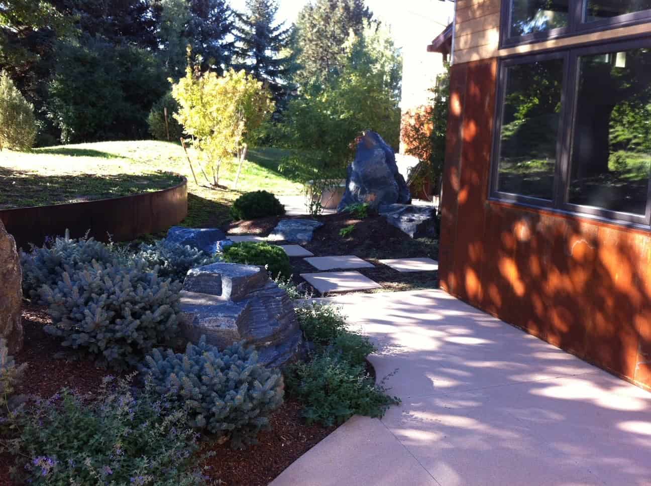 Backyard outdoor living space with patio, rock, and plants in Colorado.