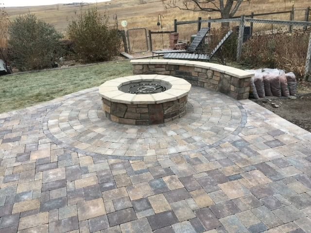Paver patio with seat wall and lighting in Colorado backyard